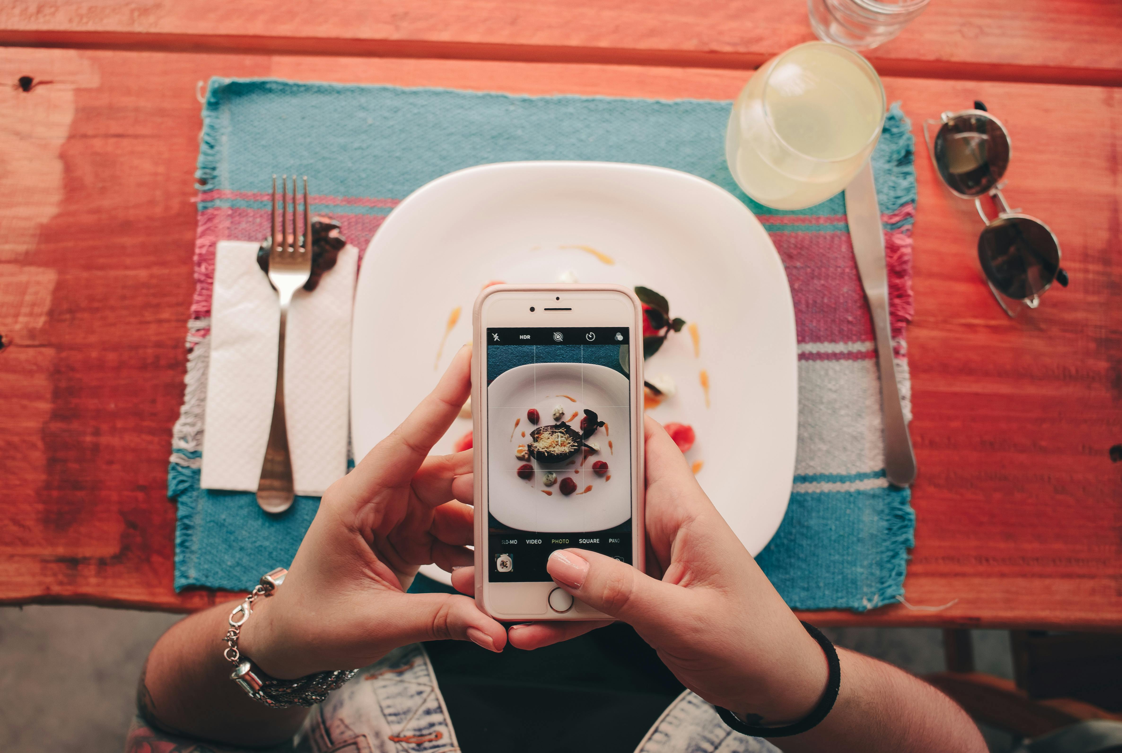 An image of hands taking a picture of a meal with a smartphone